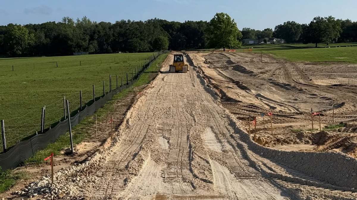 Subdivision entrance during grading in Dade City FL — dirt road with dozer
