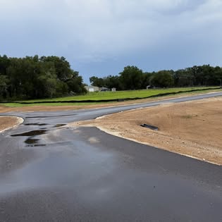 New asphalt entrance meeting graded ground