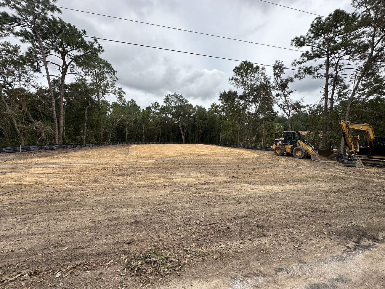 Cleared and graded lot with silt fence set, loader and excavator on site