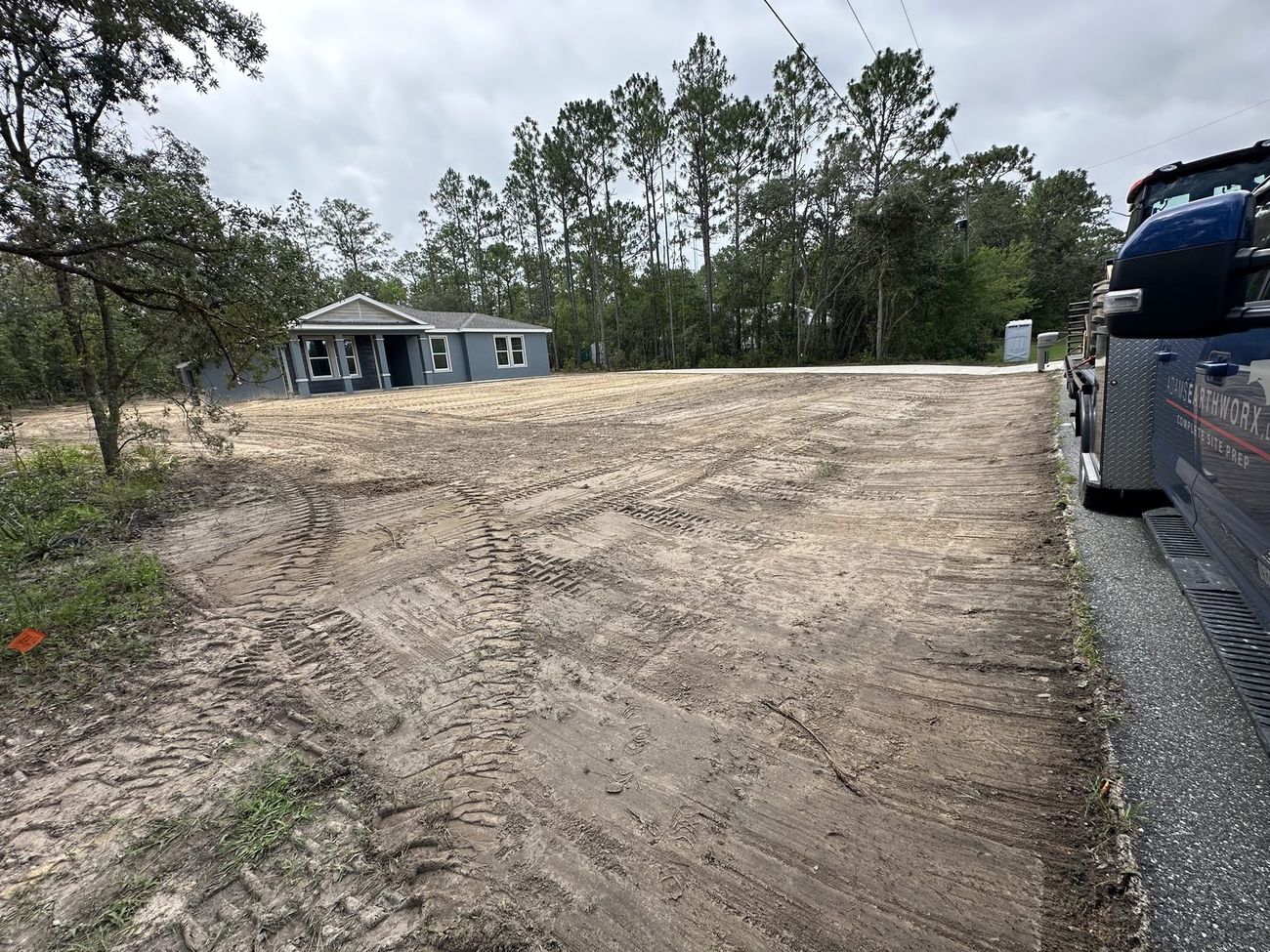Finished graded homesite lot beside a new build, Adams Earthworx truck on site