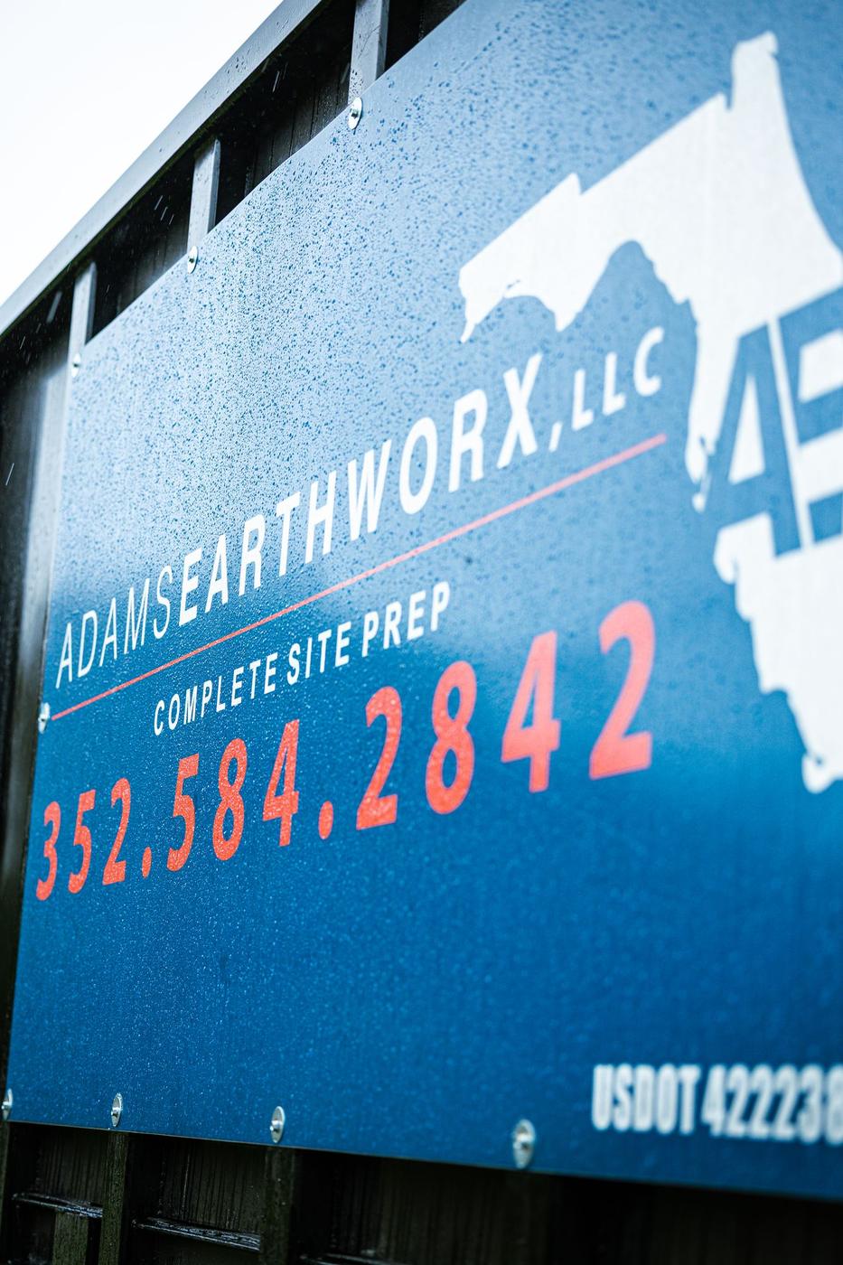 Adams Earthworx logo and phone number on the dump truck