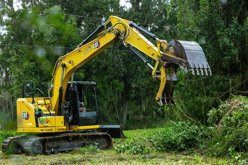 Excavator bucket raised over a brush line