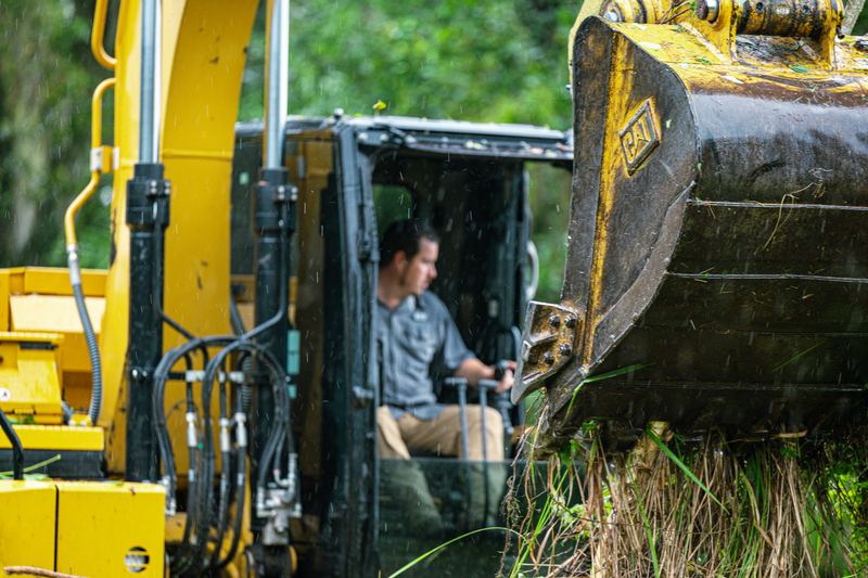 Excavator cab and bucket up close during a clearing job