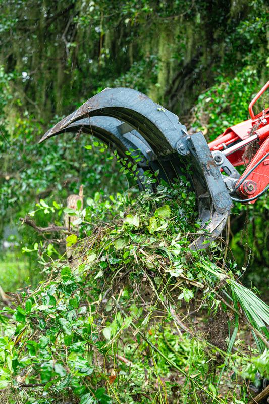 Grapple lifting a load of cleared brush