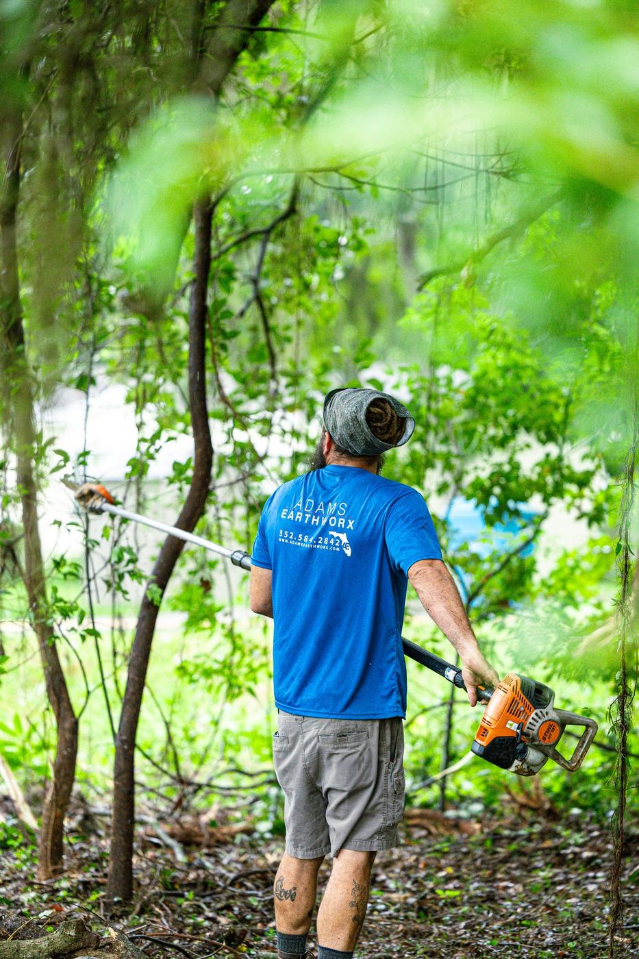 Crew member heading into the trees with a pole saw