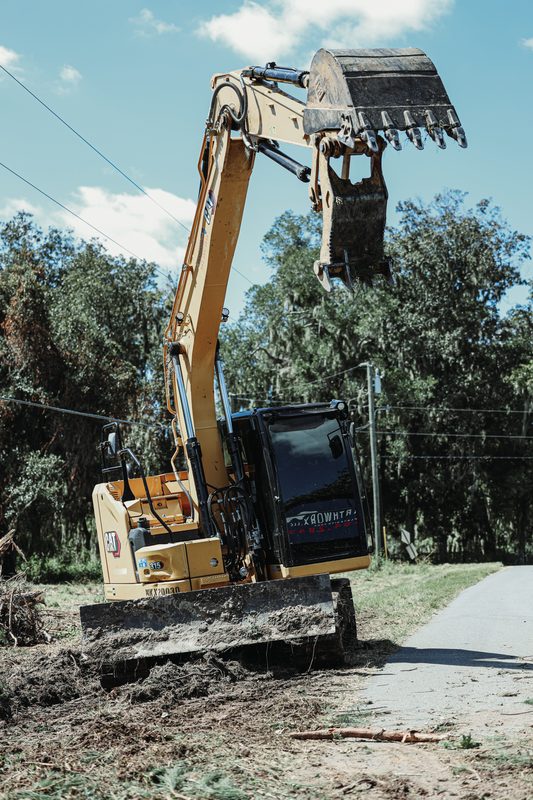 Excavator clearing brush along a roadside